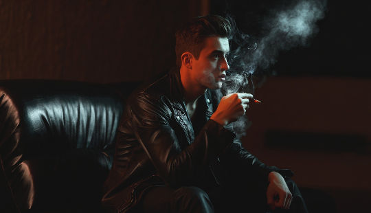 Why Are People So Emotional and Unreasonable? young man sitting in a dark setting smoking